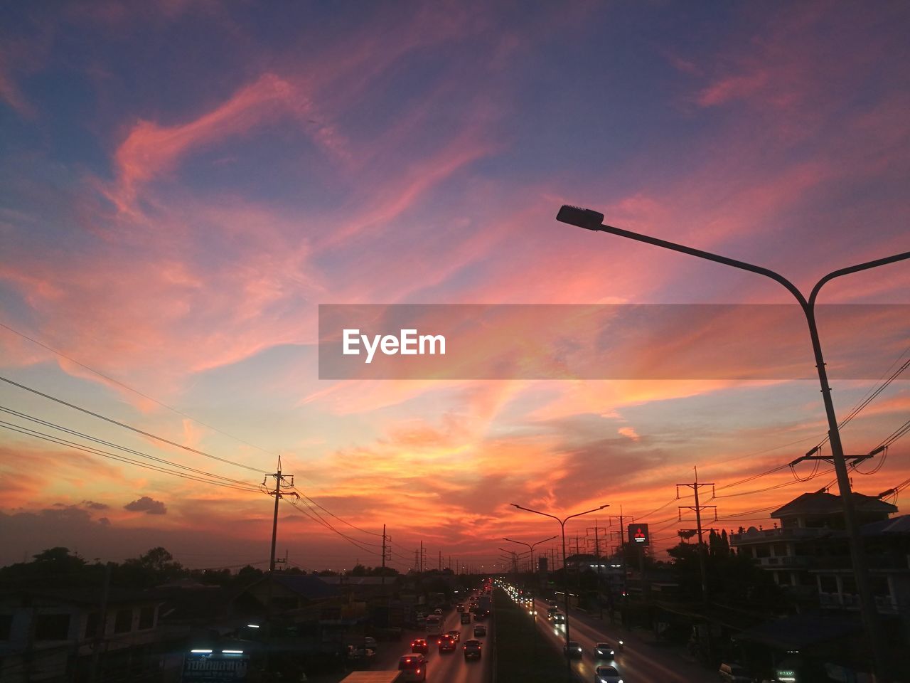 CARS ON STREET AGAINST DRAMATIC SKY