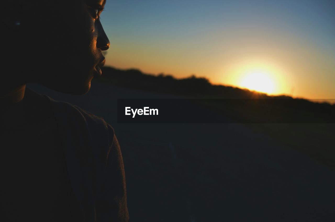 Cropped image of young woman against sky during sunset