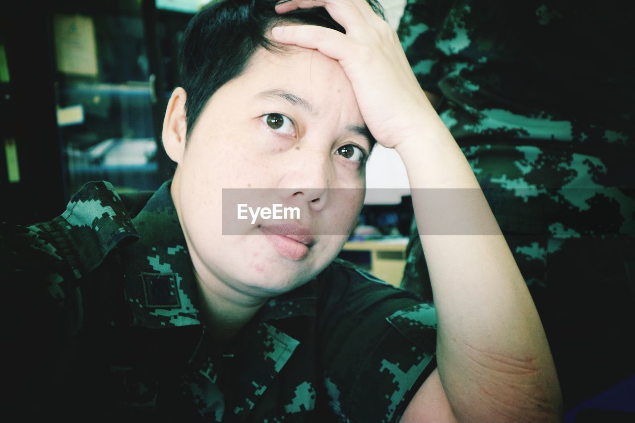 Close-up portrait of tensed female army soldier with head in hand