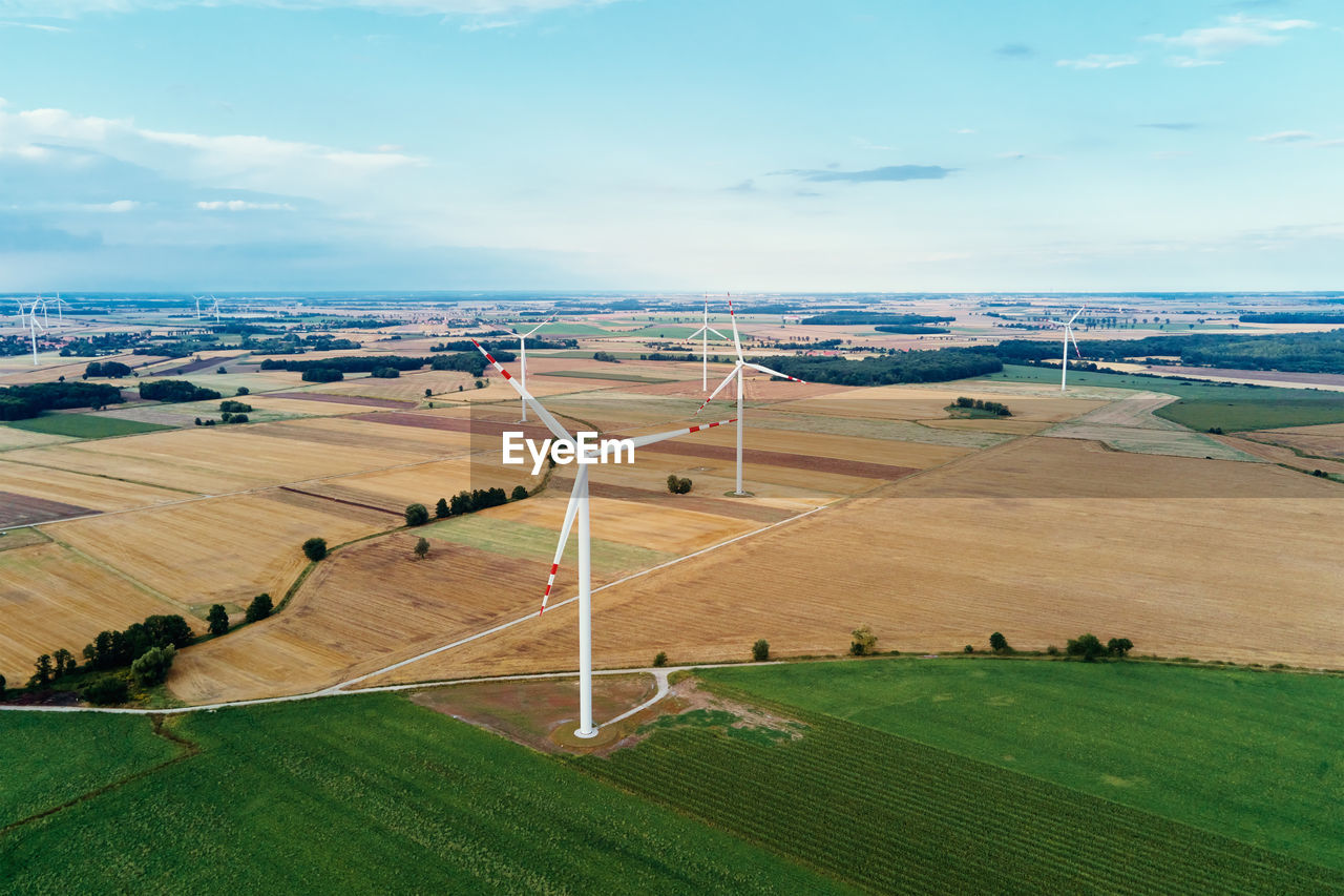 Windmill among agricultural fields. wind turbine generator at summer day