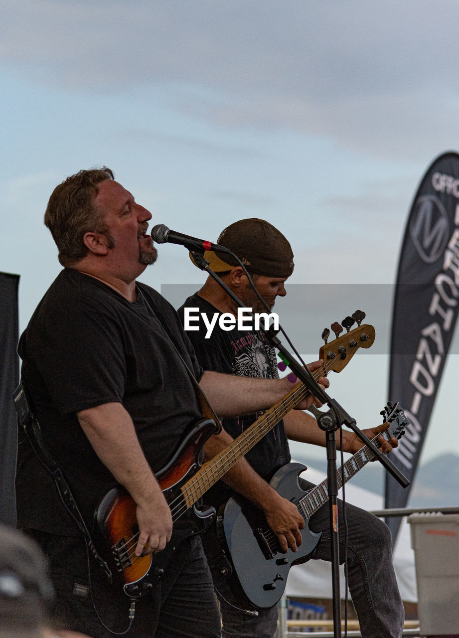 LOW ANGLE VIEW OF MAN PLAYING GUITAR AGAINST SKY