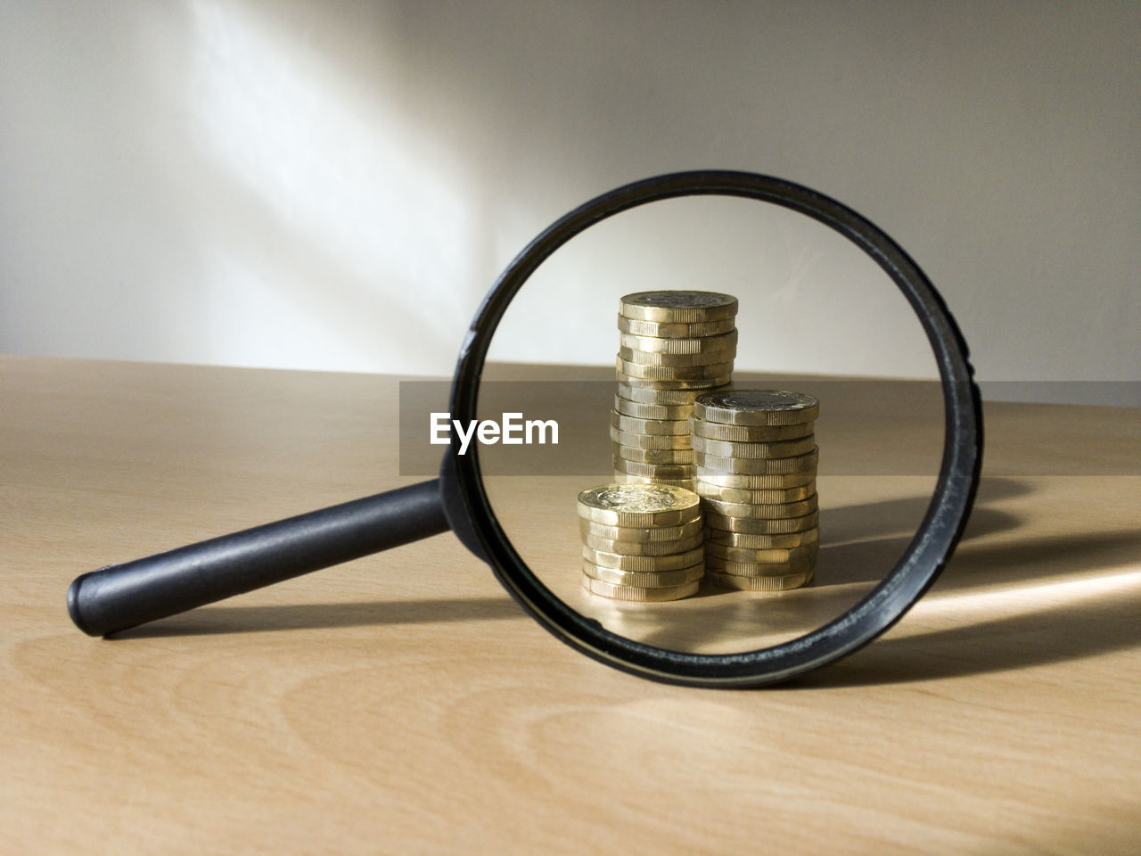 Stack of coins seen from magnifying glass on table