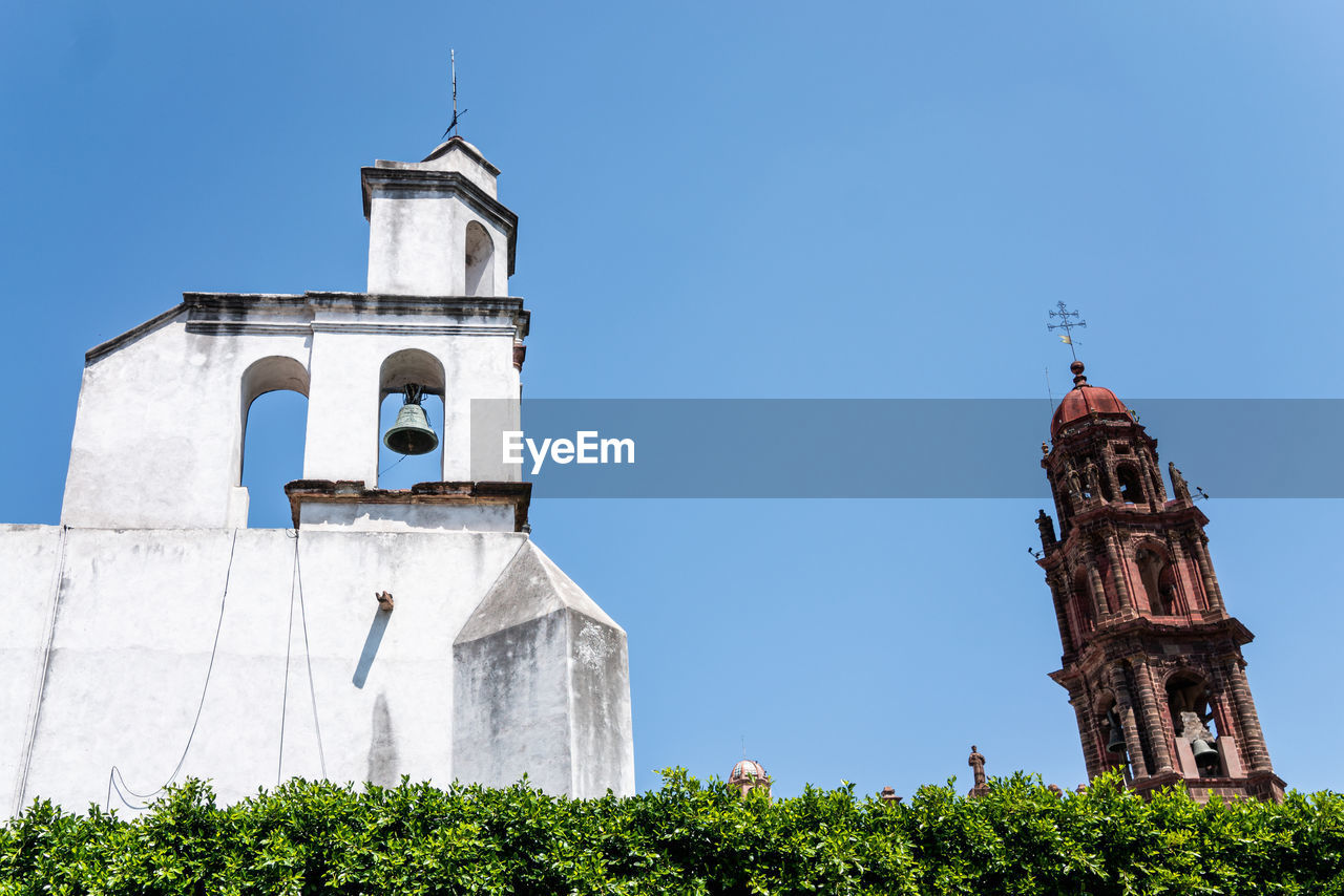 Low angle view of clock tower amidst buildings against sky