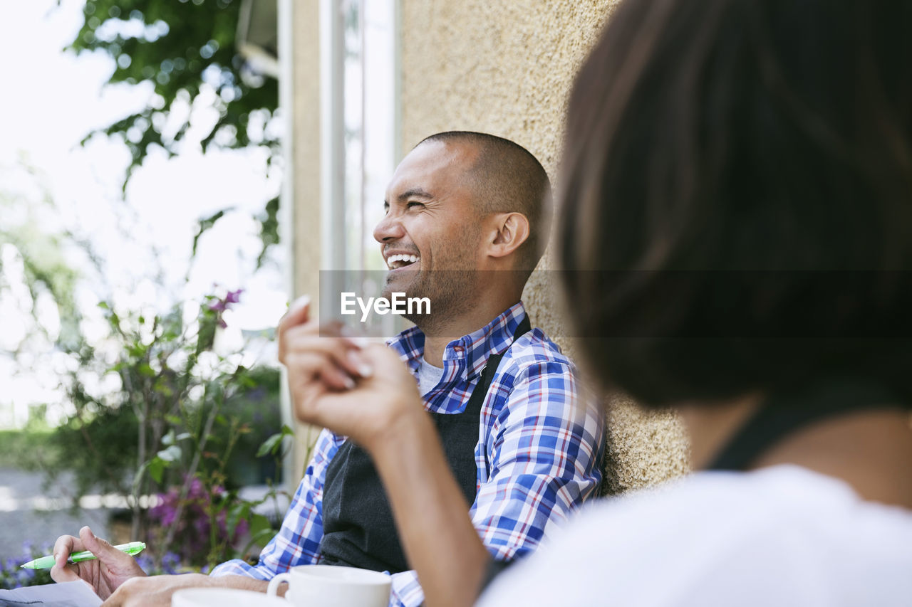 Smiling man with female colleague sitting outside cafe