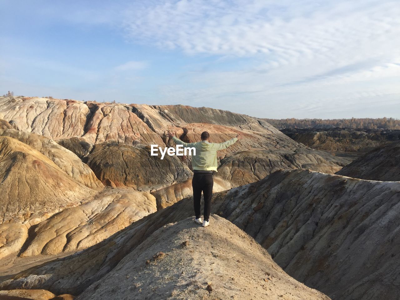 Rear view of woman standing on rock against sky