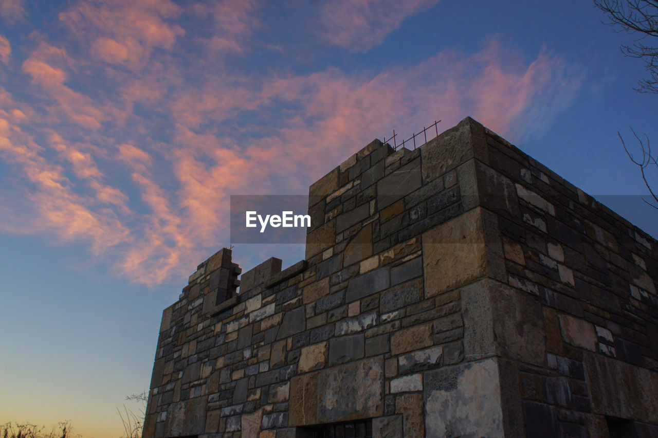 LOW ANGLE VIEW OF BUILDING AGAINST SKY AT SUNSET