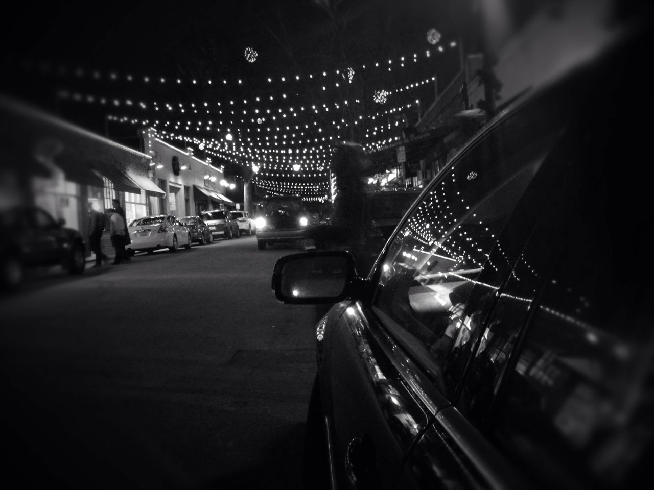 Fairy lights on empty street with parked cars at night