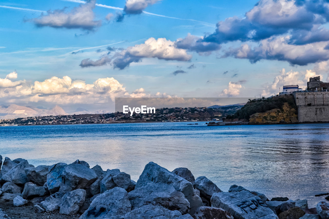 ROCKS BY SEA AGAINST SKY