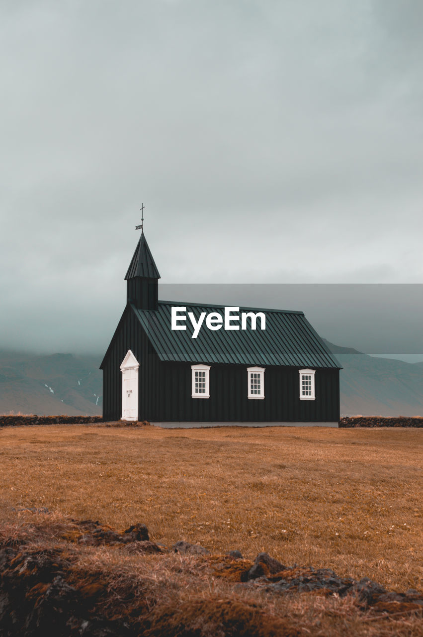 Wooden church on field against sky