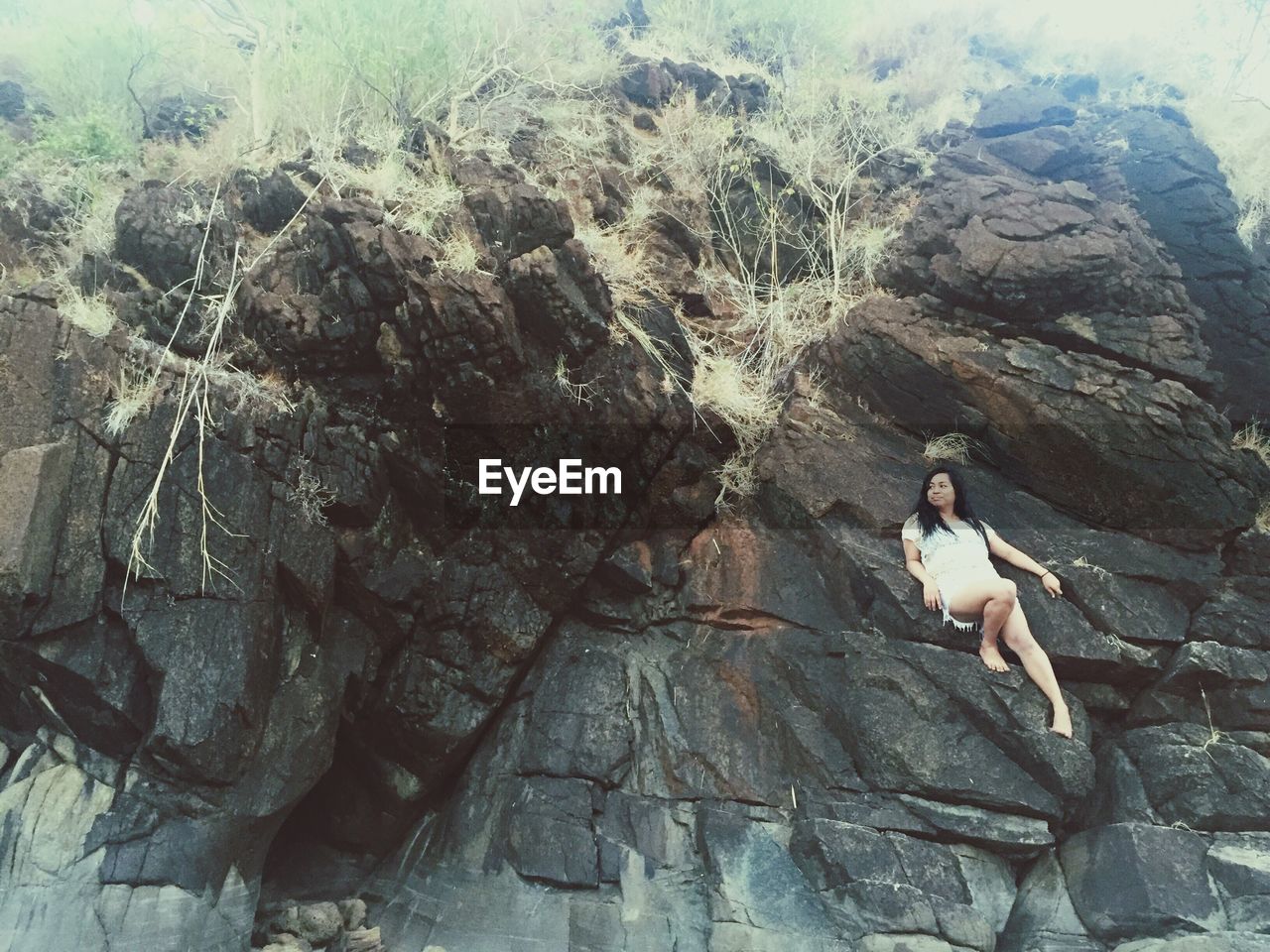 Low angle view of woman leaning on rocky mountain