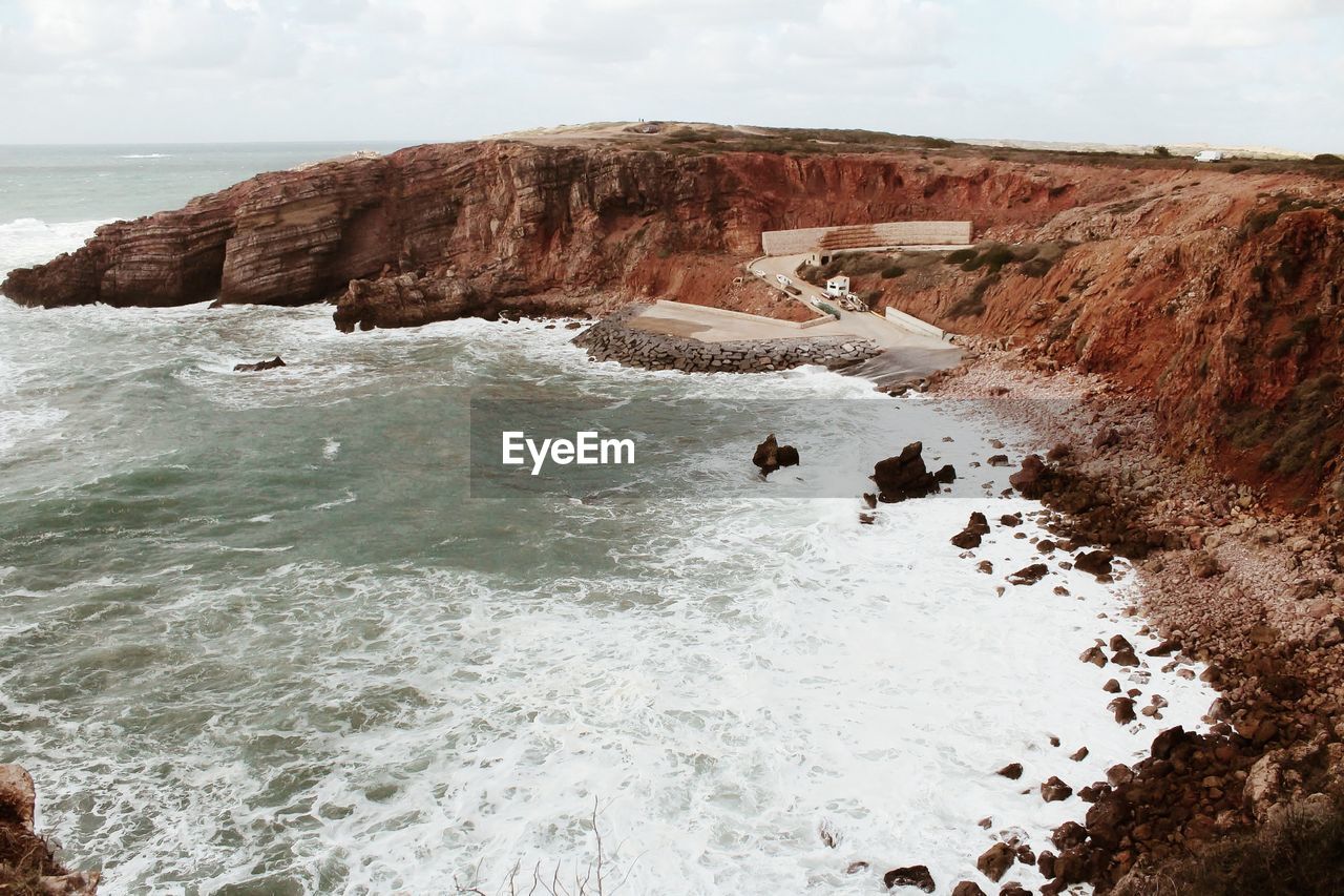 Rock formations on shore against sky