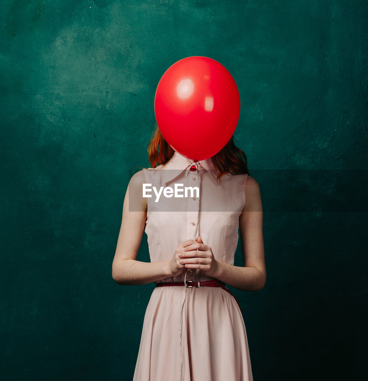 Midsection of woman with balloons against wall