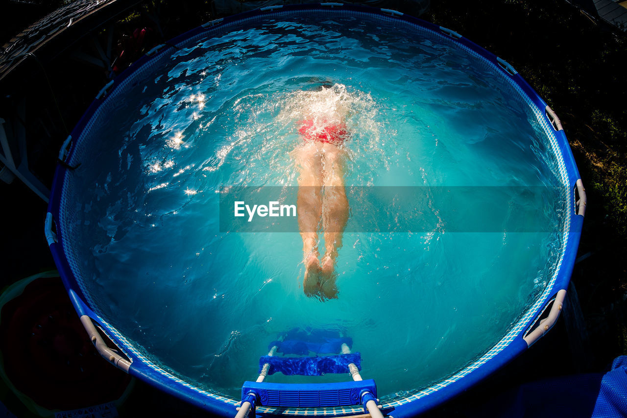 High angle view of shirtless man swimming in wading pool