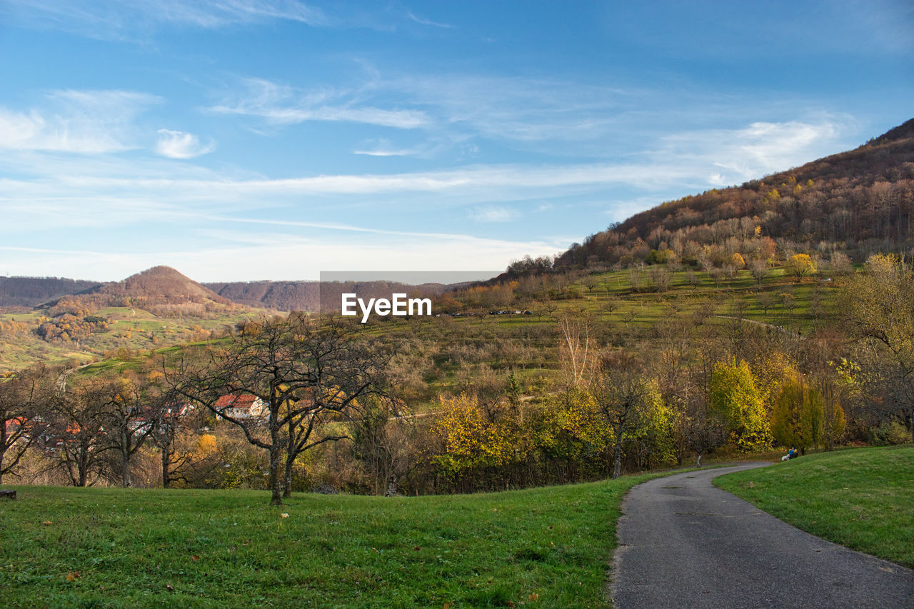 SCENIC VIEW OF ROAD BY FIELD AGAINST SKY