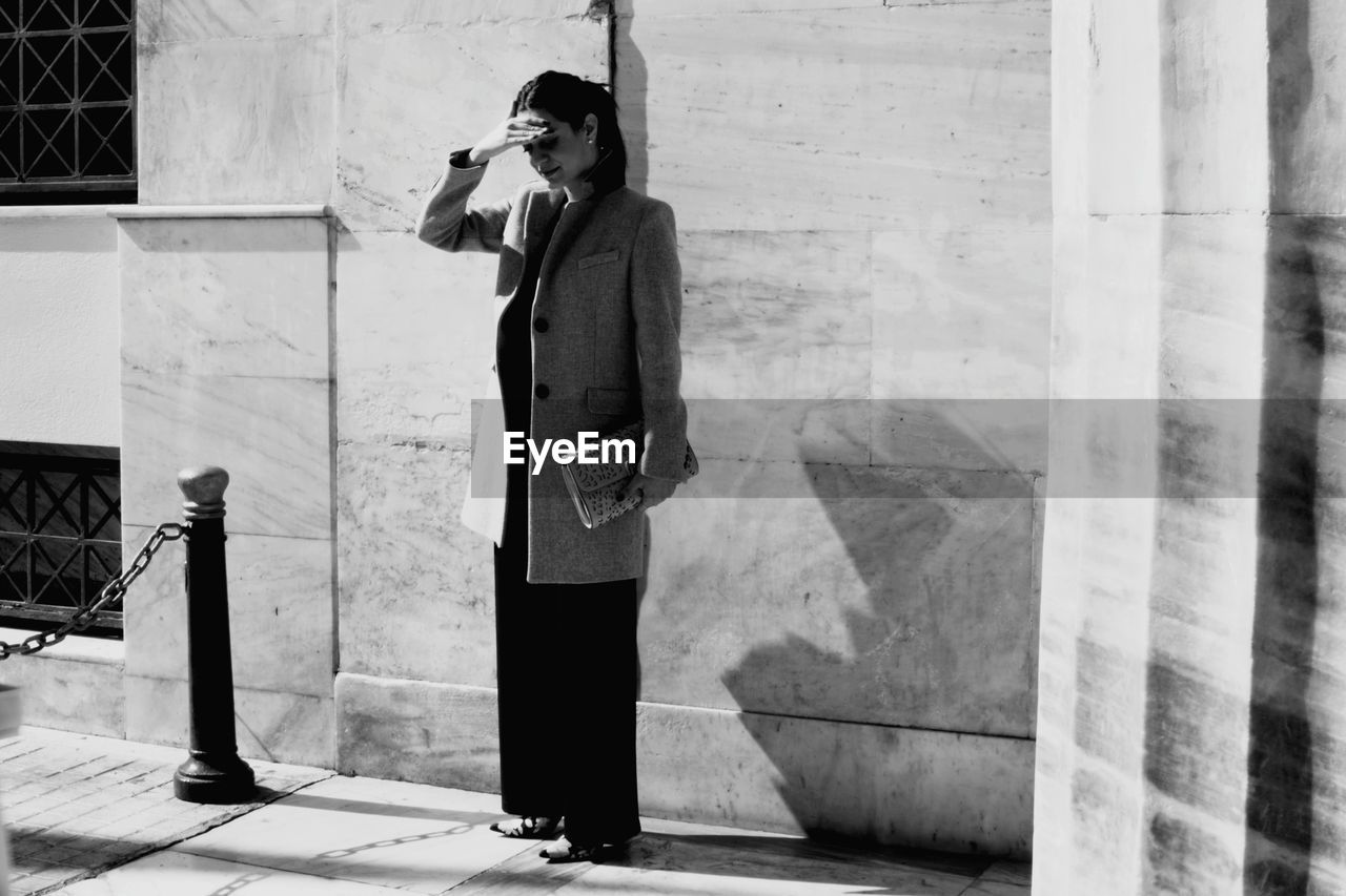 Full length of woman standing against building