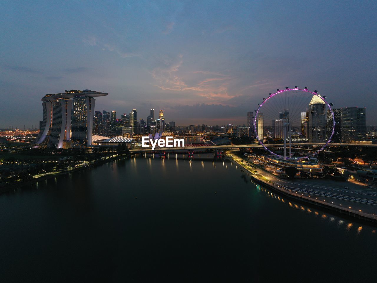 Illuminated city by river against sky  at benjamin sheares flyover, singapore