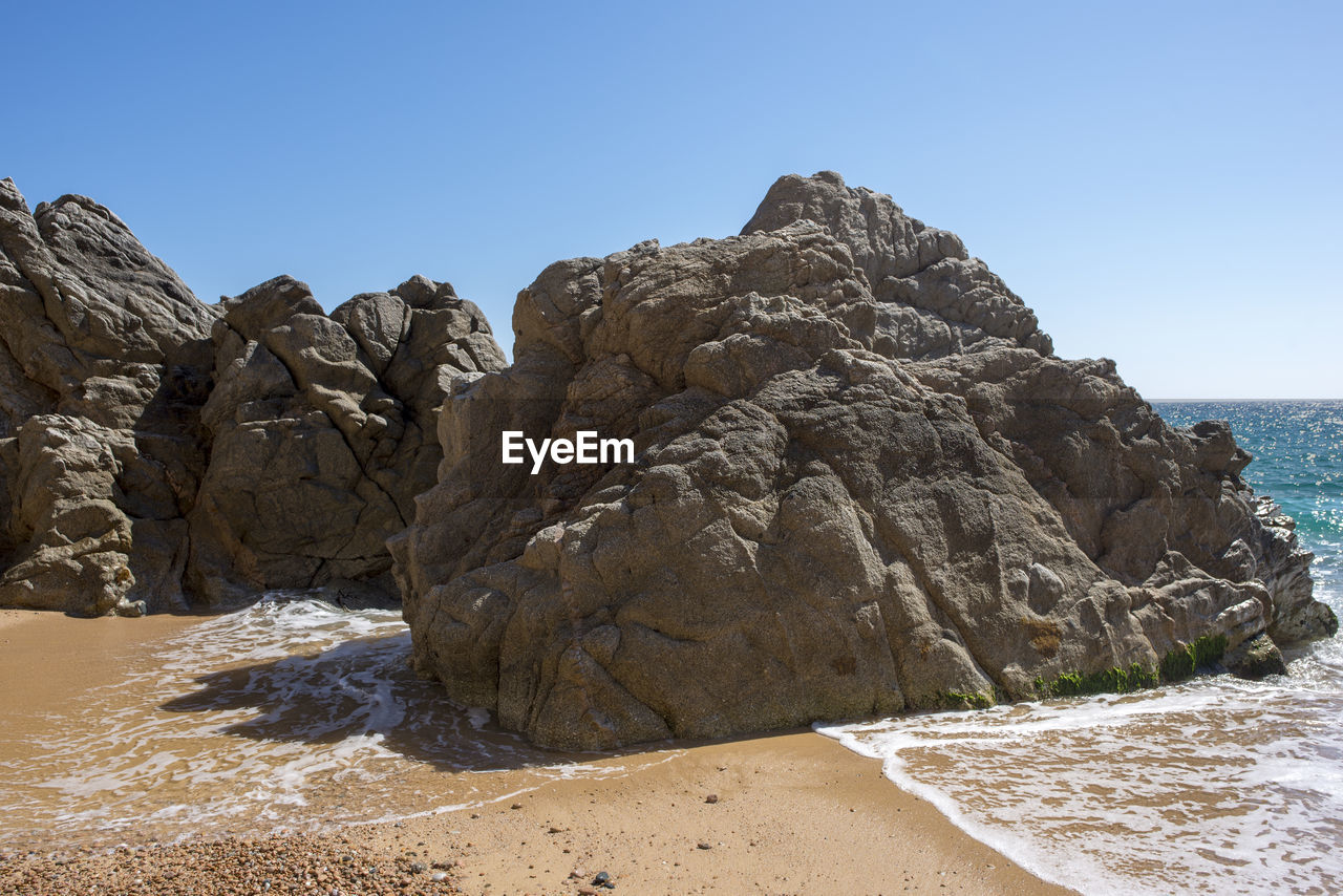 Rock formation on beach against clear sky