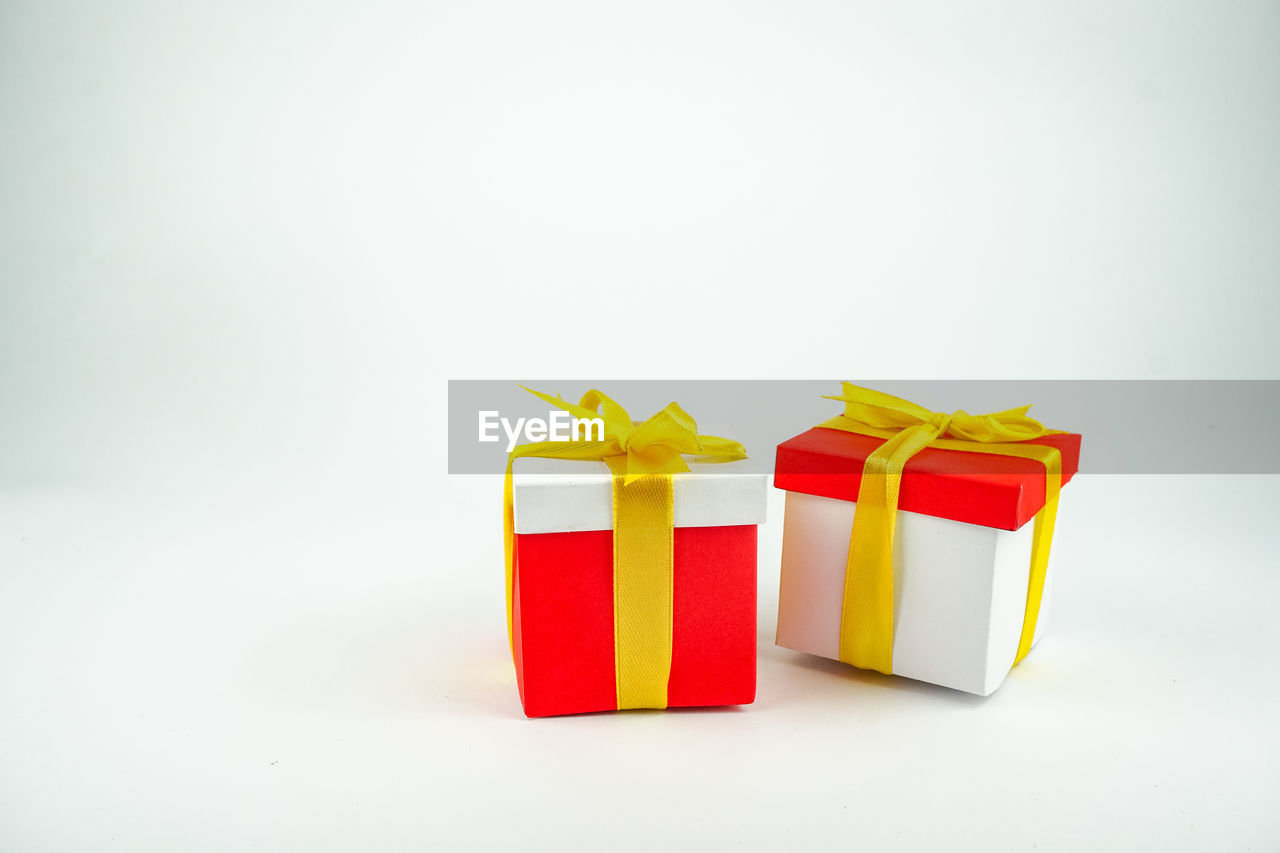 yellow, gift, holiday, studio shot, indoors, red, celebration, box, orange, copy space, christmas present, ribbon, no people, gift box, present, bow, surprise, container, white background, group of objects, multi colored, tied bow, wrapping paper, still life, paper, event