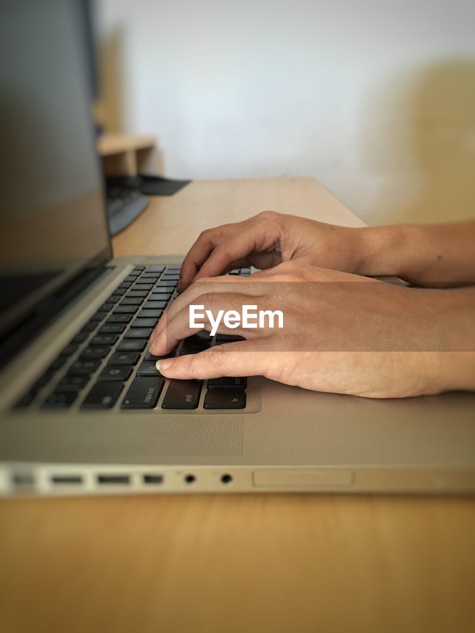 Cropped hands of businesswoman using laptop on table