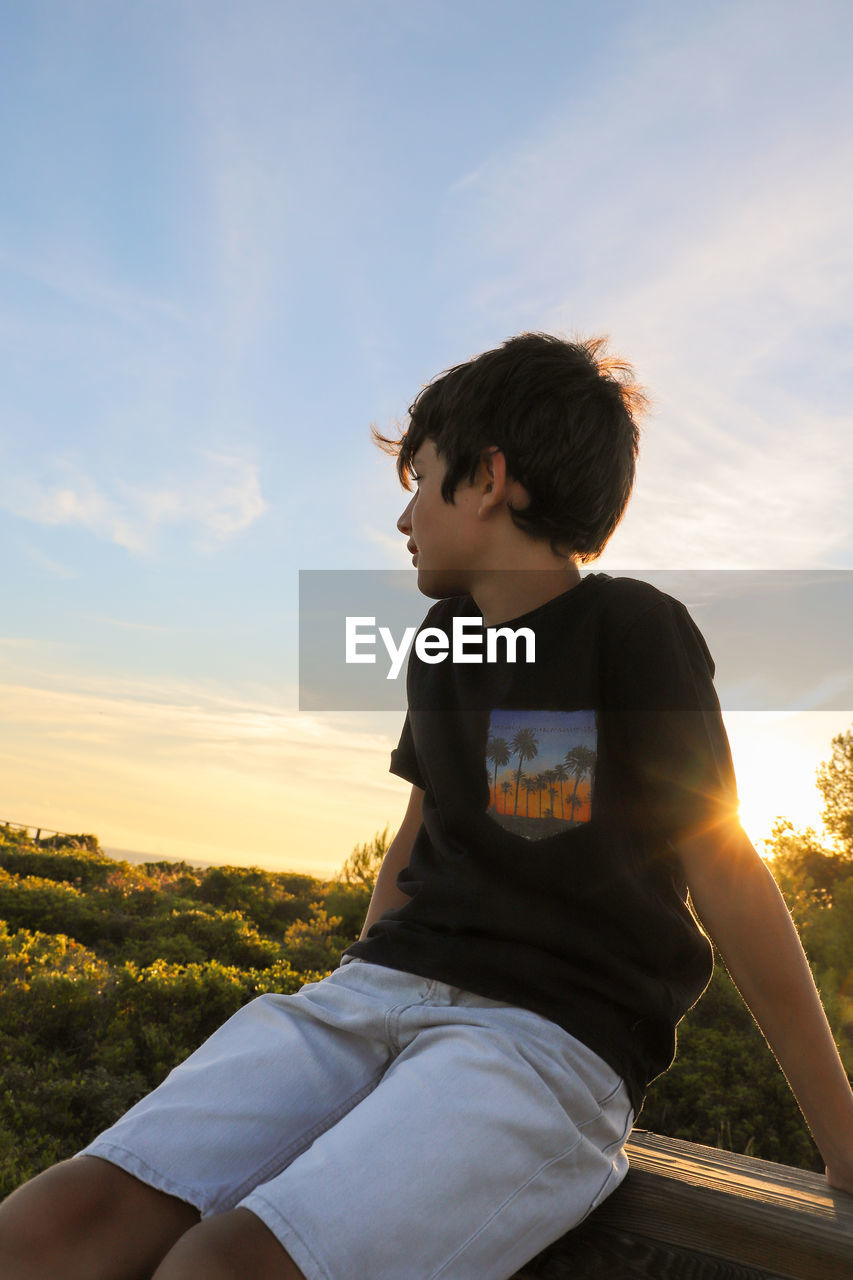 BOY LOOKING AT CAMERA AGAINST SKY