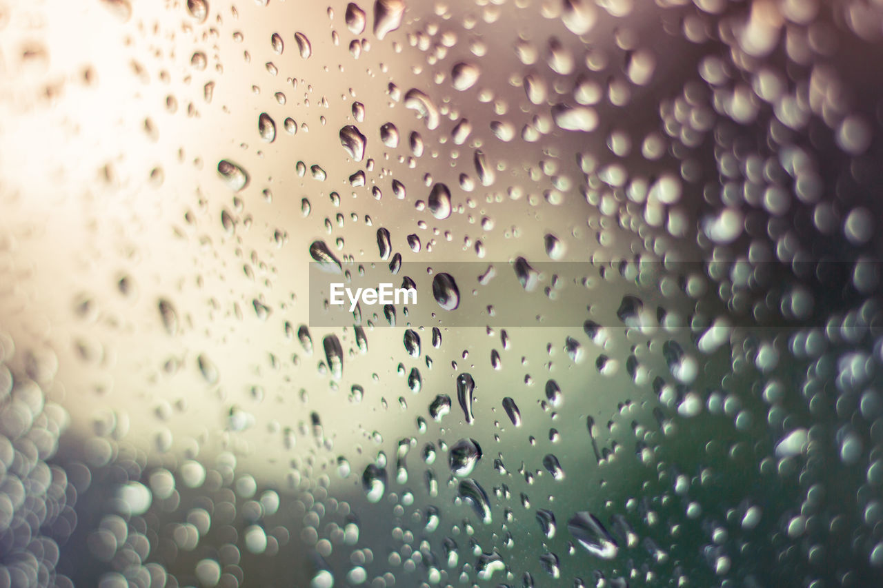 CLOSE-UP OF RAINDROPS ON GLASS WINDOW