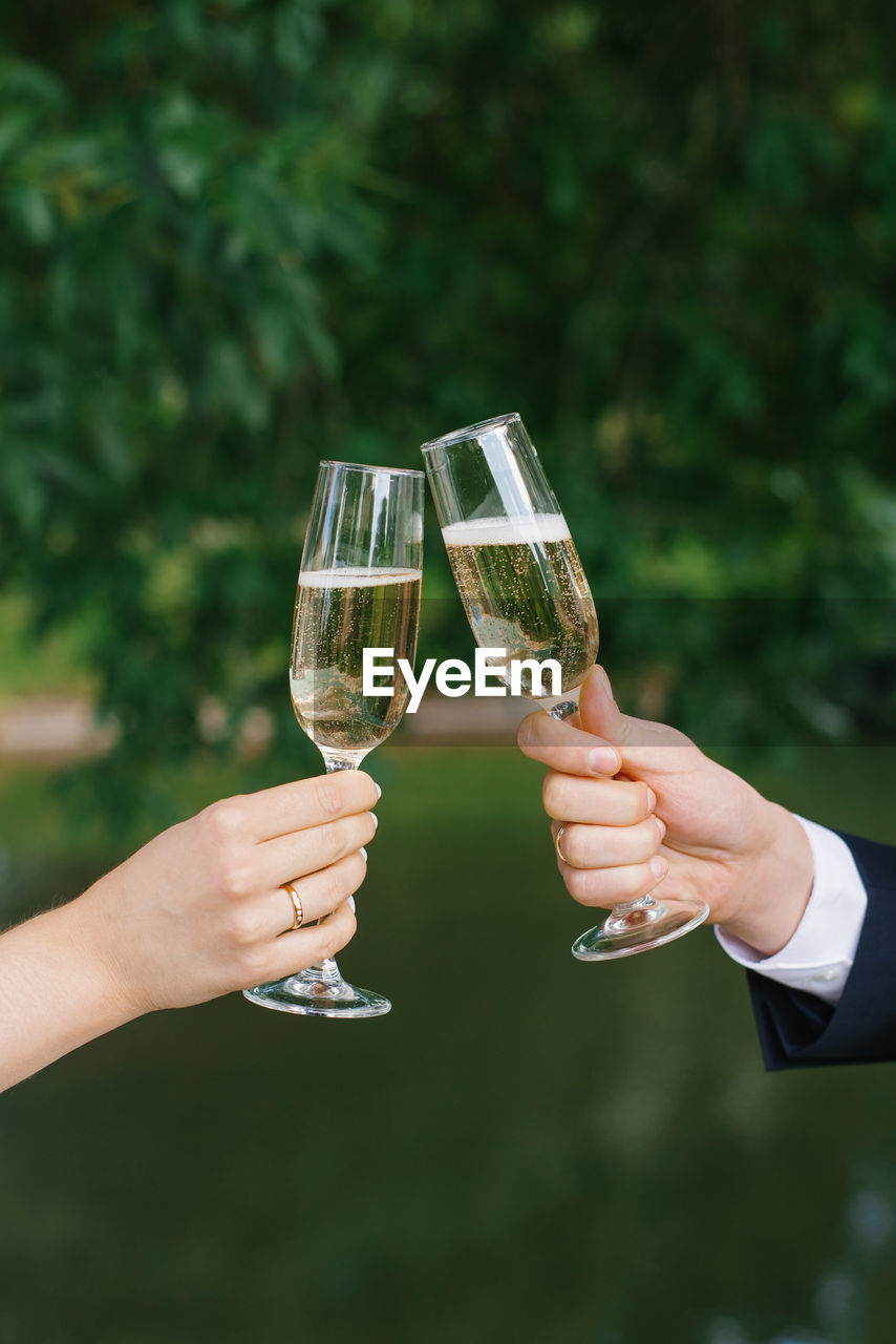 Newlyweds are holding glasses of champagne in their hands