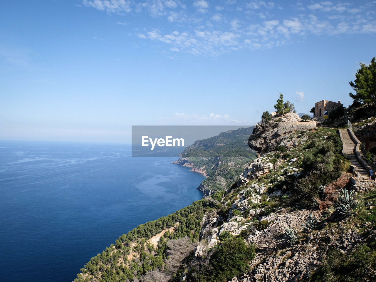 Scenic view of mountain by sea against blue sky