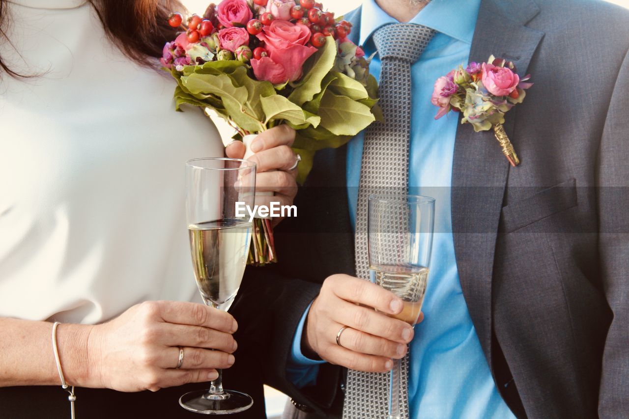 Midsection of people holding flower bouquet