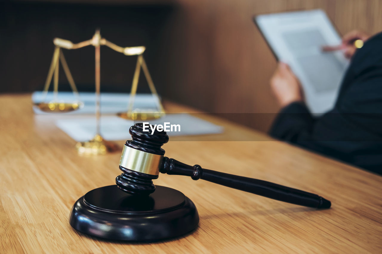 Midsection of lawyer with data sitting by gavel and weight scale on desk