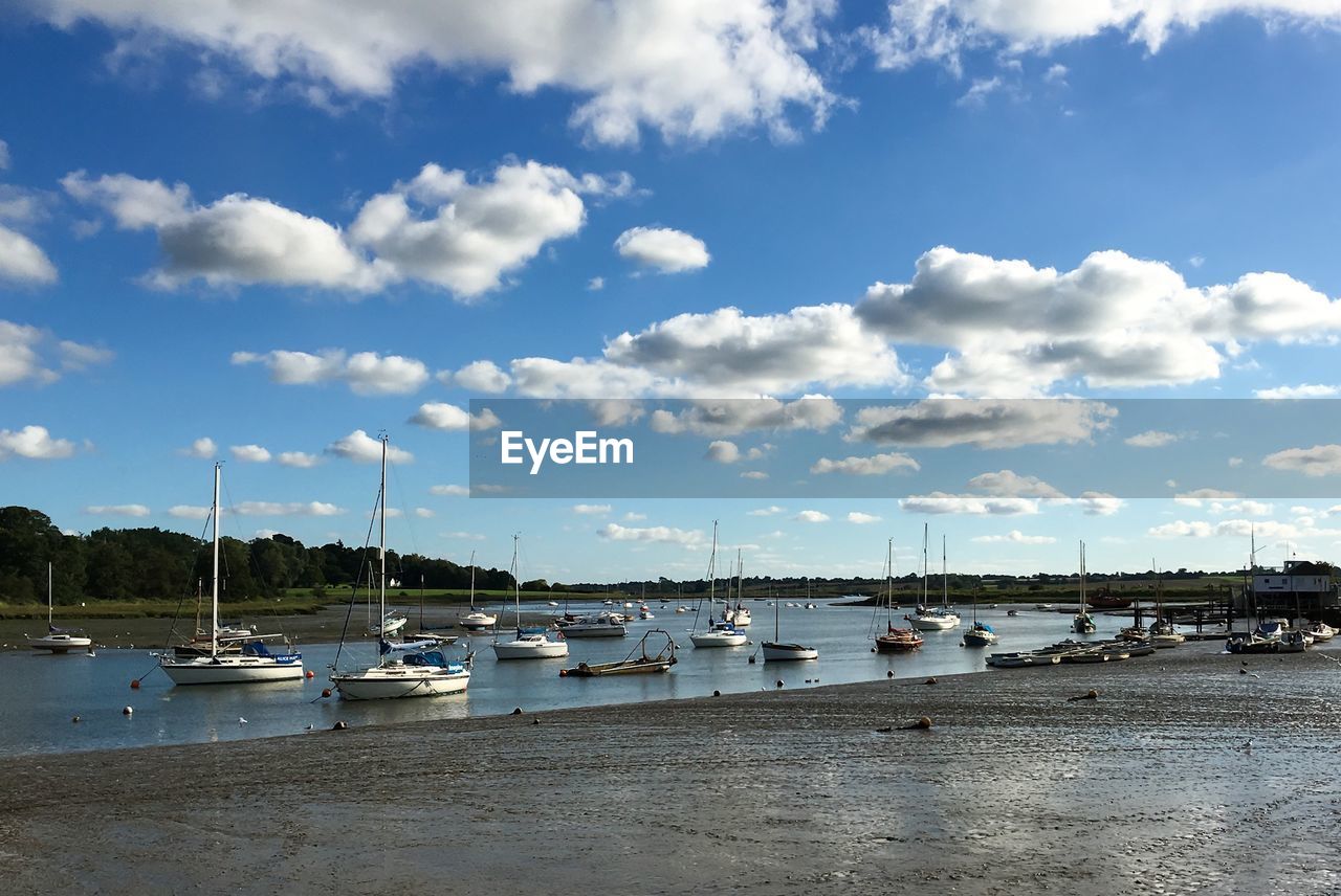 Boats anchored at port against sky