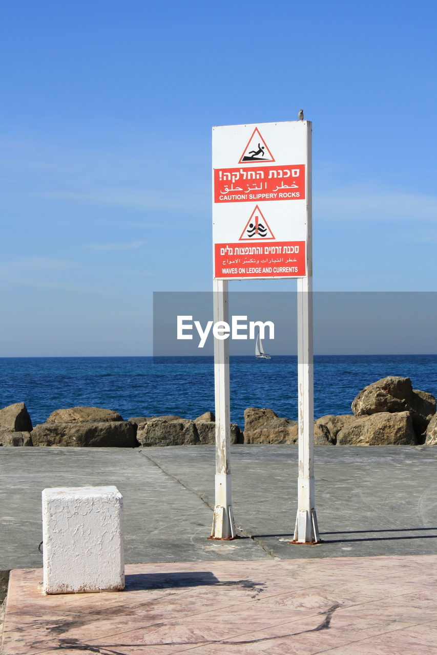 Information sign on beach against sky