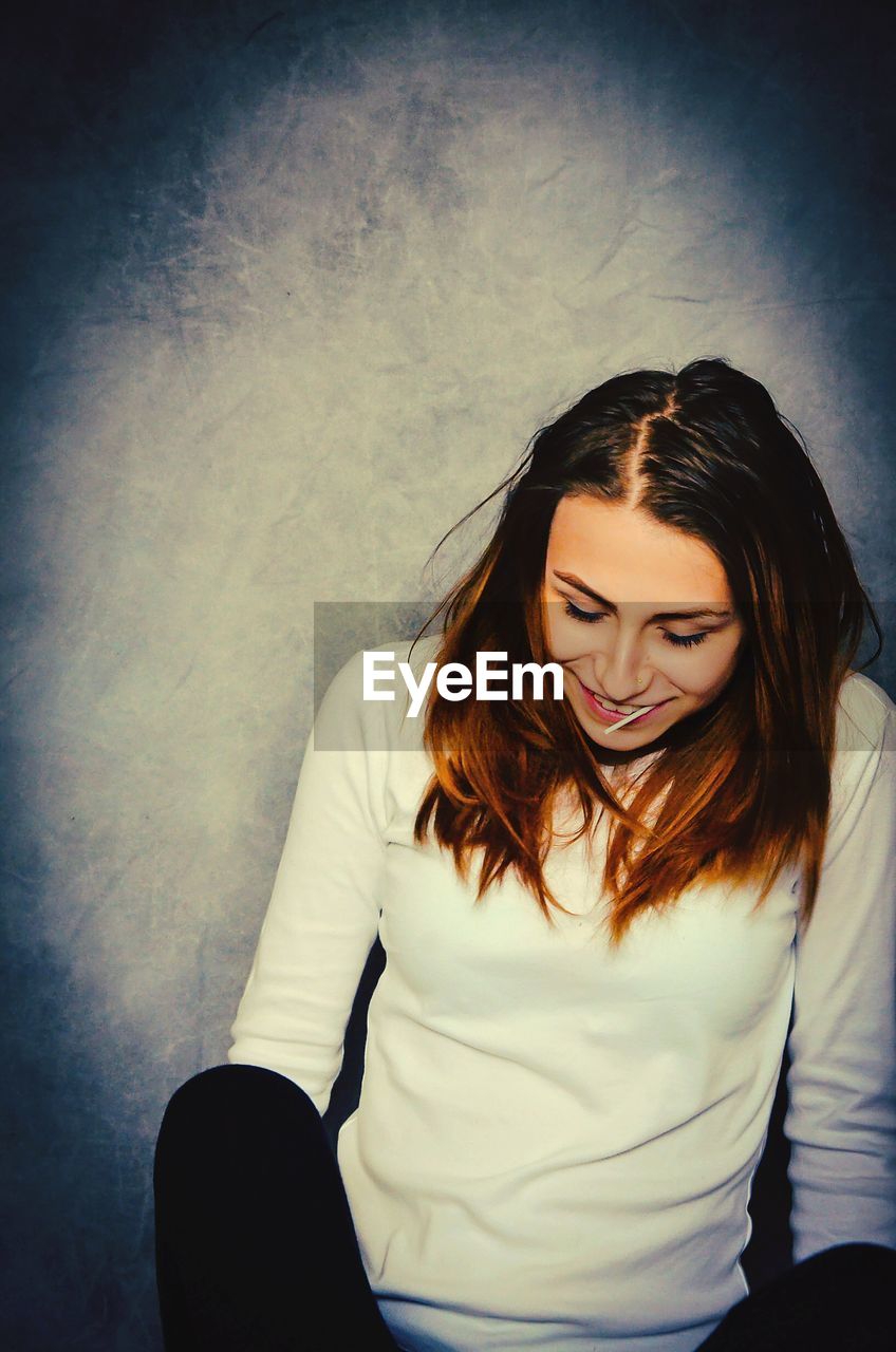 Smiling young woman against wall