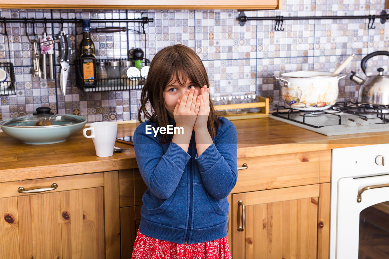Girl looking away while standing in kitchen
