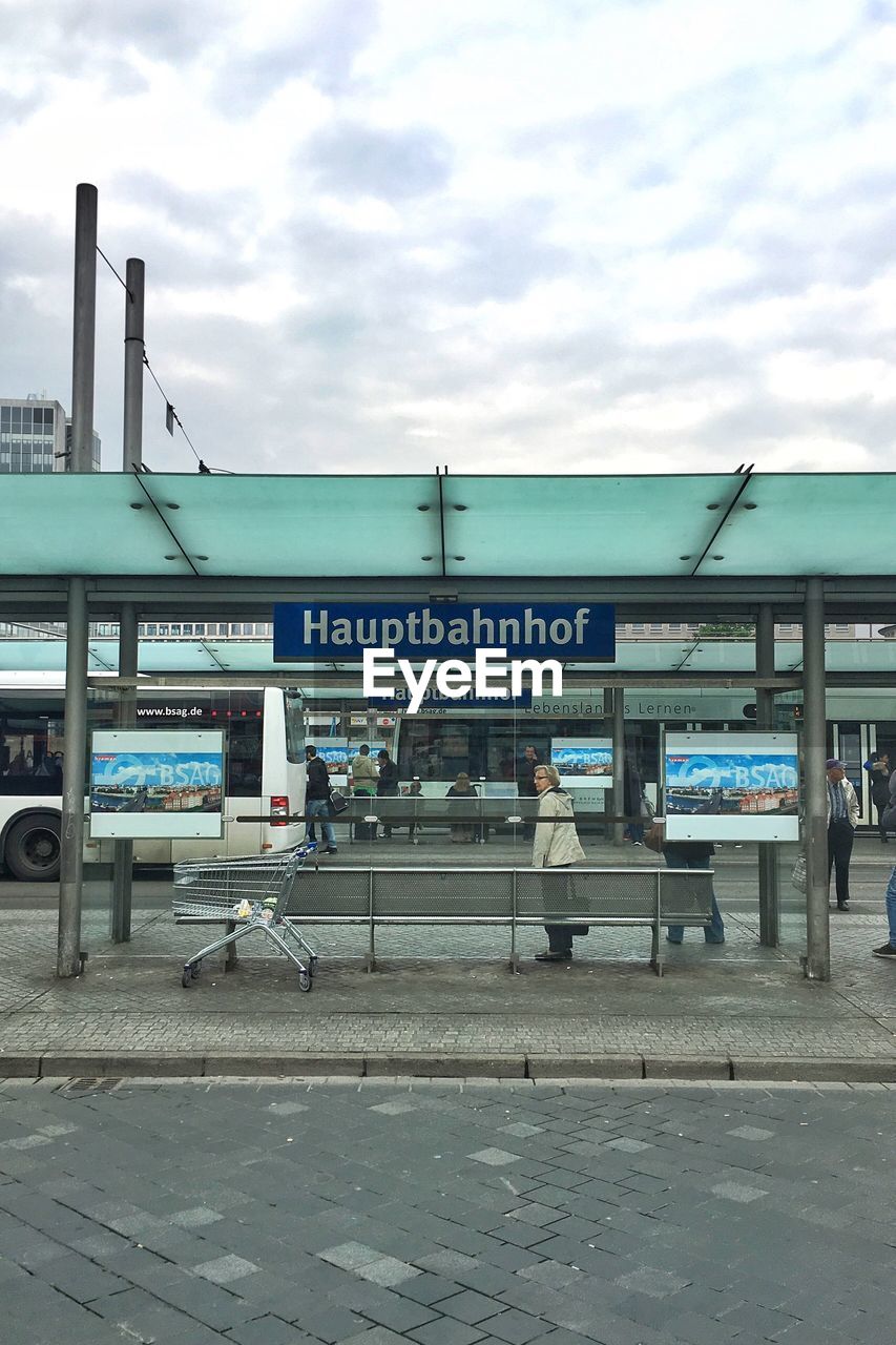 Man standing at bus stop against sky