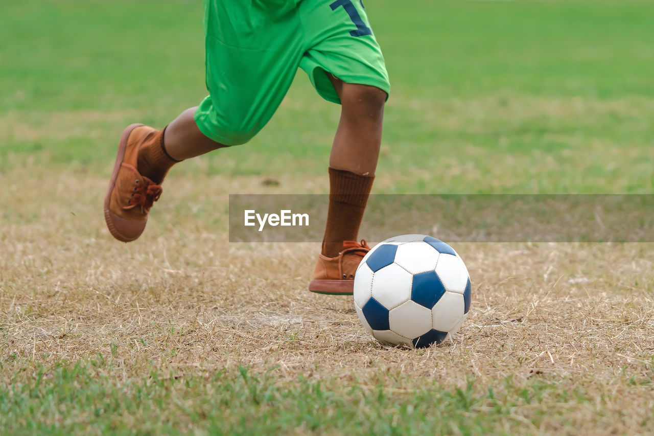 low section of man playing soccer at park