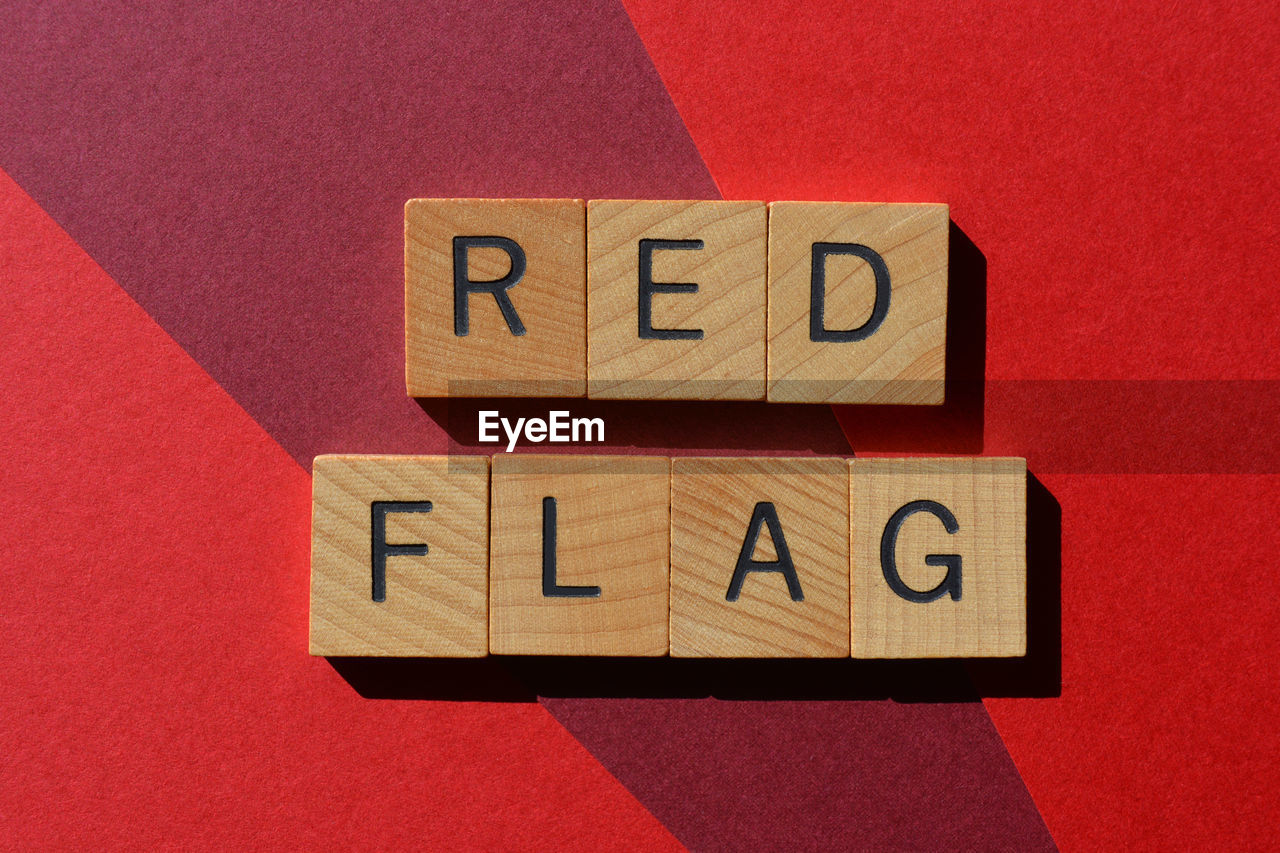 Red flag, words in wooden alphabet letters isolated on red background as banner headline