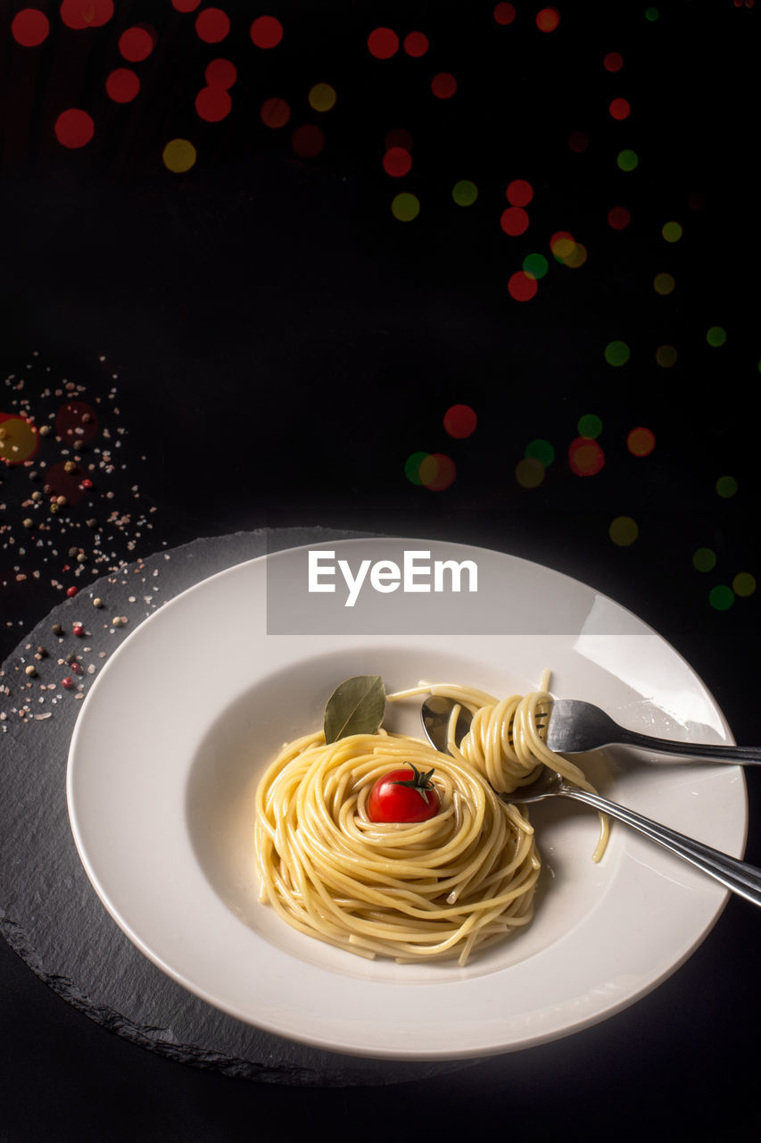 Food concept with spaghetti and cherry tomatoes on illuminated b