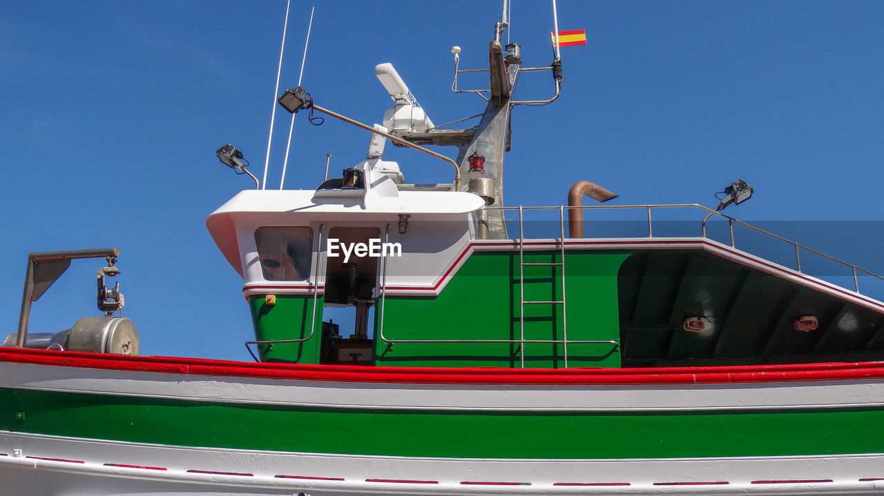 Low angle view of ship moored on sea against clear blue sky