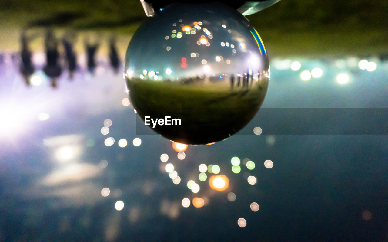 Reflection of firework display on crystal ball on field at night