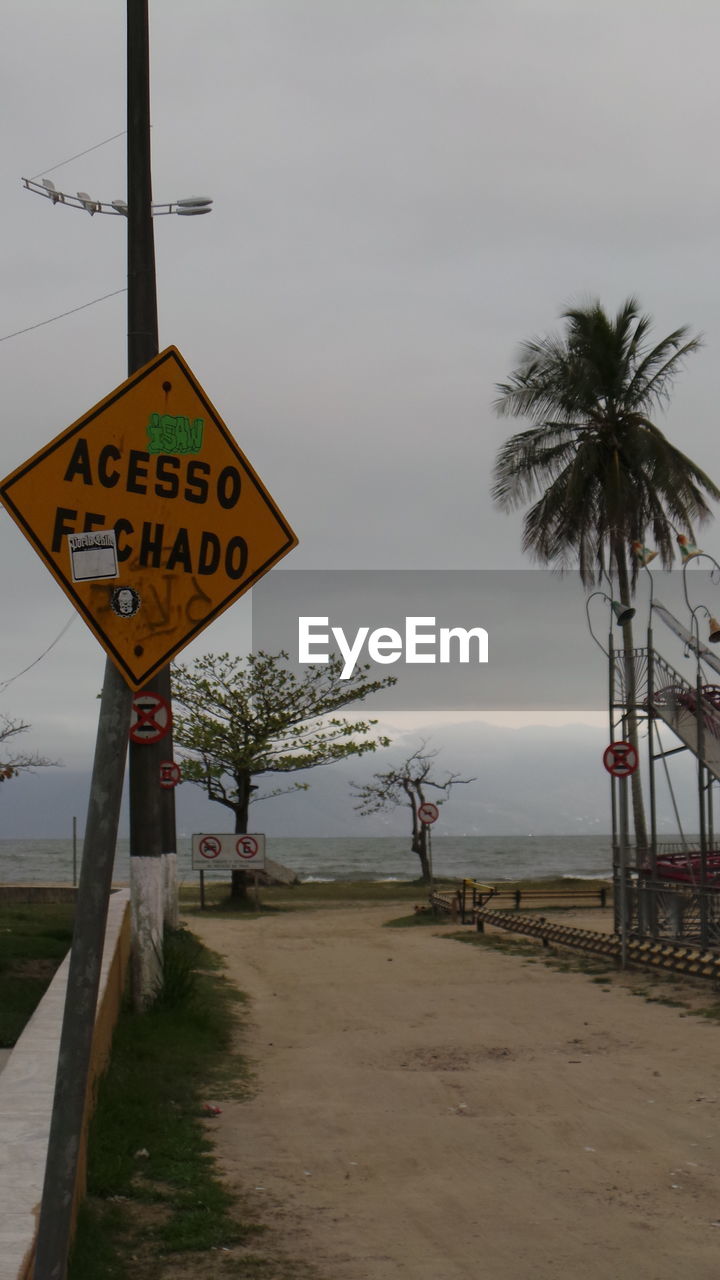 Road sign by sea against sky