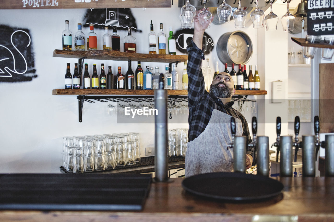Bartender arranging wineglasses while standing at bar counter