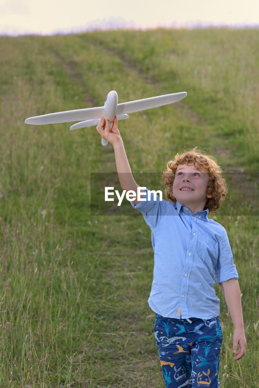 Boy playing with toy airplane on grassy field