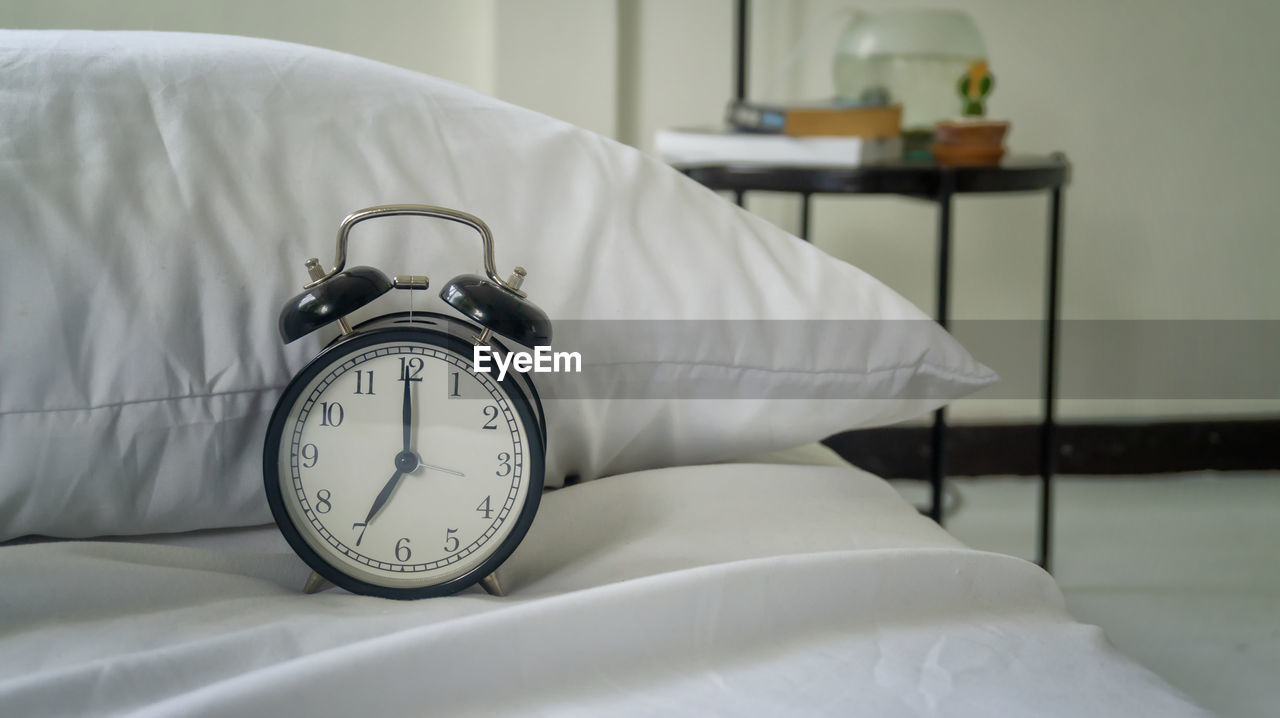 Close-up of alarm clock on bed