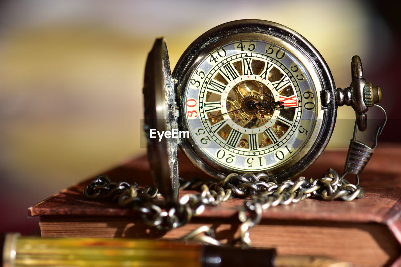 Close-up of pocket watch on book