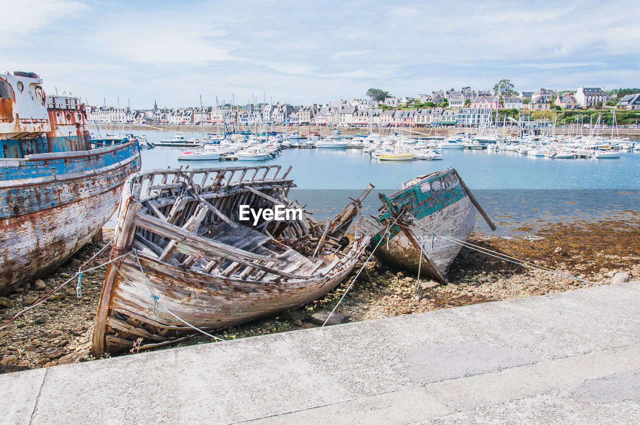 BOATS MOORED ON BEACH AGAINST SKY