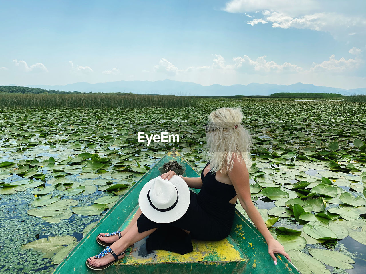 Woman wearing hat against plants against sky