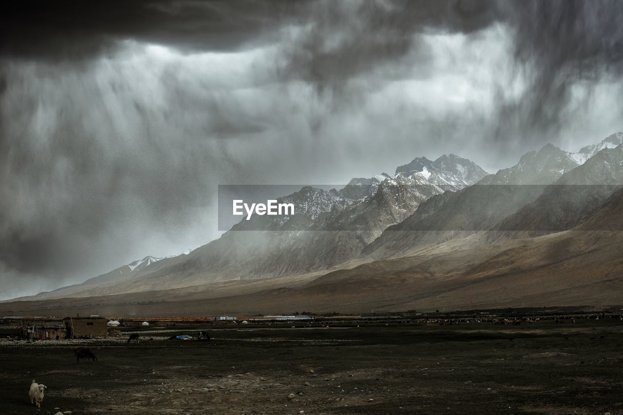 The towering snow-capped mountains next to the alar wetland are about to be covered by storm