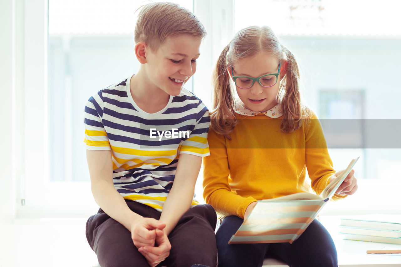 Cute sibling reading book at home