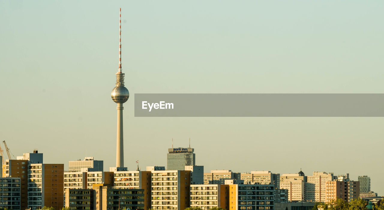 Communications tower in city against clear sky