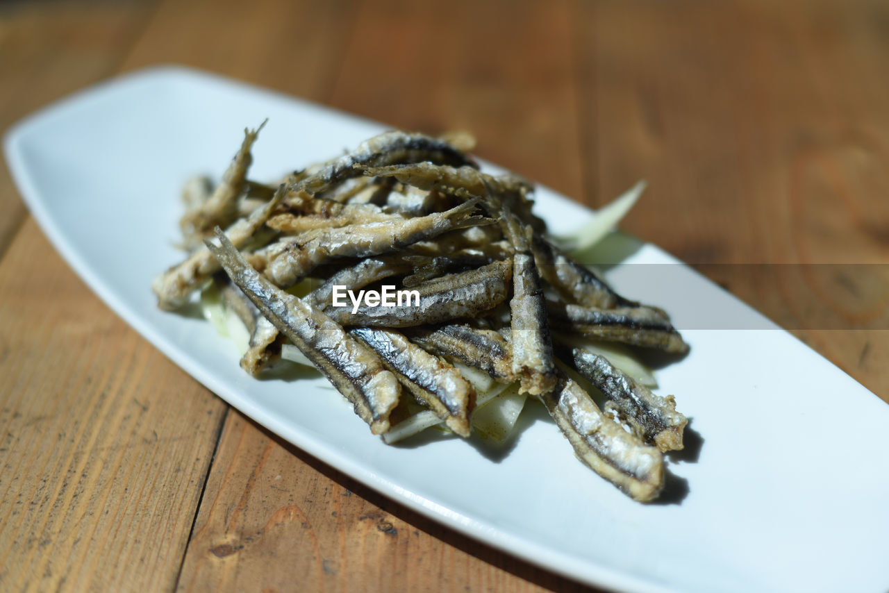 High angle view of fried fish in plate on wooden table